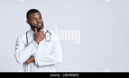 Thoughtful black doctor in white uniform looking at copy space Stock Photo