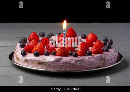 Home made Birthday Cheesecake with berries and Birthday candles. Cheesecake with Strawberry, blueberry and raspberry on grey wooden background. Stock Photo