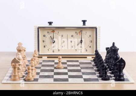 Close up side view of chess board with all the pieces after first move with analog chess clock Stock Photo