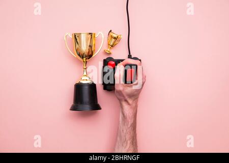 winning gamer. Hand using a retro games joystick with a gold winning trophy Stock Photo