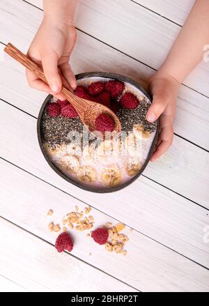 Woman's hands holding raspberries smoothie bowl on white background. Top view. raspberries and chia seeds im smoothie bowls topped with frozen berries Stock Photo