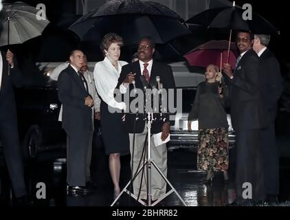 Alexandria Virginia, USA October 15, 1991Mrs, Virginia Thomas wife of now Associate Justice of the United States Supreme Court, Clarence Thomas stands behind Thomas at the microphones for a short news conference under umbrellas during a rain shower to acknowledge the vote of the Senate Judiciary Committee confirming his nomination as Associate Judge to the Court. On the far left is Senator Strom Thurmond (Republican of South Carolina) and on the far right is Senator John Danford (Republican of Missouri) Credit: Mark Reinstein/MediaPunch Stock Photo