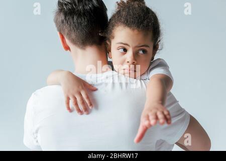 back view of foster father taking away sad african american daughter isolated on white, custody concept Stock Photo