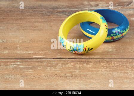 Close-up image of an yellow and blue bracelets on brown wooden background. Stock Photo