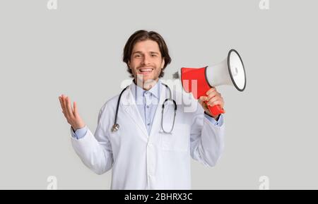 Medical Announcement. Portrait Of Positive Young Doctor With Loudspeaker In Hands Stock Photo