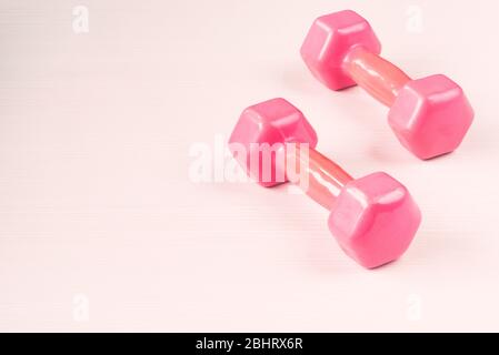 Close-up image of two pink dumbbells isolated on white wooden background Stock Photo