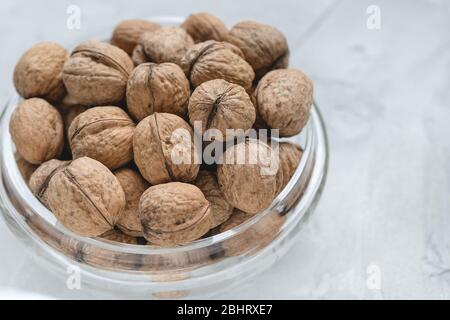 Uncracked walnuts in shell in bowl on gray background, concept of healthy eating vegan food. Close up, selective focus, copy space. Stock Photo