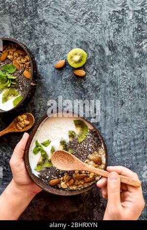 Smoothie bowls with mixed tropical fresh fruits on table with hands, top view.Healthy vegan food breakfast Stock Photo