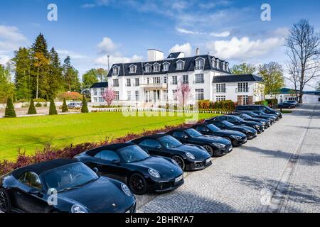 Germany, Munich, 26 April 2019: Aerial video of the group of black sports cars are before the white building of hotel in a sunny weather, luxury life Stock Photo