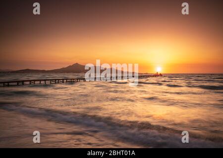 Majorca Puerto de Alcudia beach pier at sunrise with colorful cloudscape in Alcudia bay in Mallorca Balearic islands of Spain Stock Photo