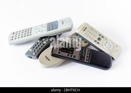 An assortment of old TV and video remote controls piled up on a white background Stock Photo