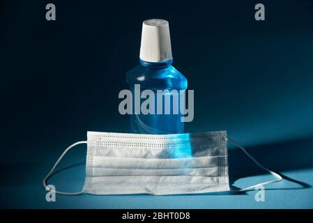 blue sanitizer in a large bottle and a medical face mask. dark background Stock Photo