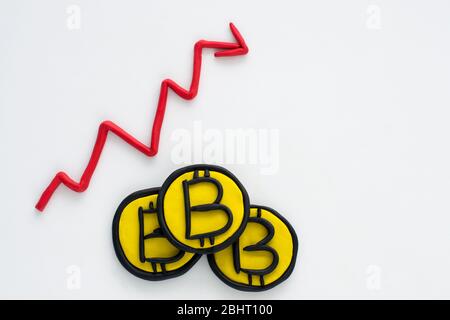 Rise of the bitcoin rate, stack of three coins and arrow graphics made from plasticine Stock Photo