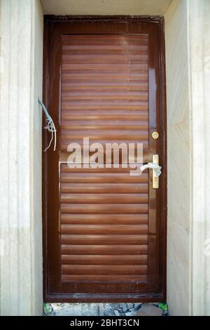 Brown wall. Gold flowers. Microphone and camera to see the person at the door. Black copper metal door. Stock Photo