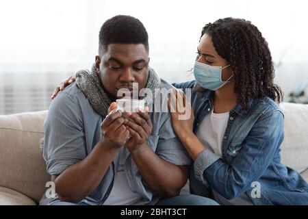 Caring Black Wife Looking After Her Ill Husband With Coronavirus At Home Stock Photo