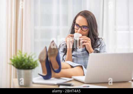 Businesswoman having feet up, drinking coffee, having a break in the office. Stock Photo