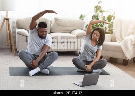 Young Happy African American Couple Training Together In Front Of Laptop Stock Photo