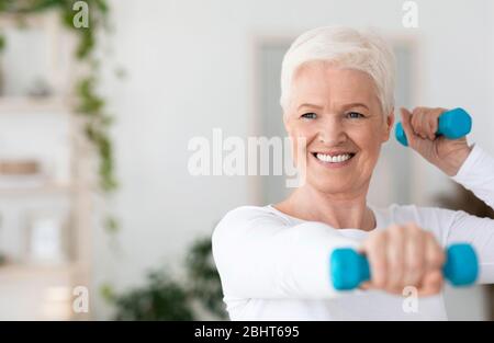 Portrait Of Happy Elderly Woman Exercising With Dumbbells At Home