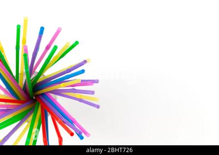 Disposable plastic multicolored tubules for drinks in glass on white background, copy space. Festive concept, party, birthday. Flat lay, top view. Hor Stock Photo