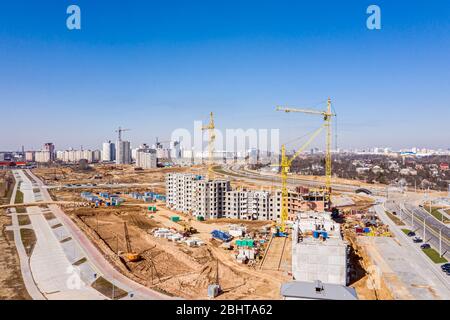 new apartment buildings under construction and tower crane against blue sky. aerial view from flying drone Stock Photo