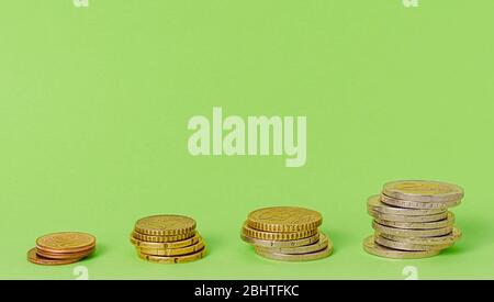 Stacks of euro coins on green background. Copy space Stock Photo