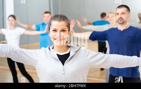 Young smiling woman practicing vigorous lindy hop movements in dance class Stock Photo