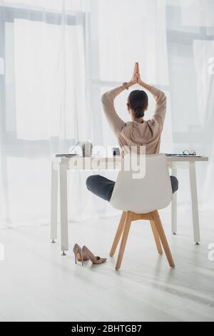 Back view of businesswoman meditating with namaste gesture at workplace with incense stick Stock Photo