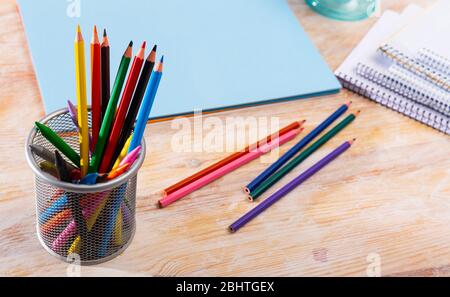 Image of multicolored wooden pencils on desk with papers and notebooks Stock Photo