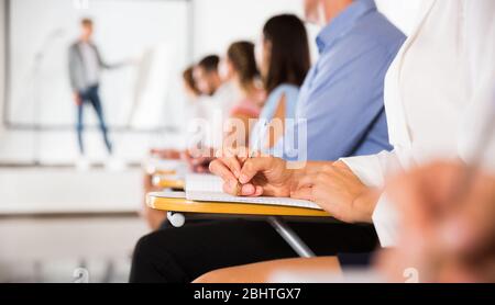 Woman making notes during lecture, focus on female hand with pen Stock Photo