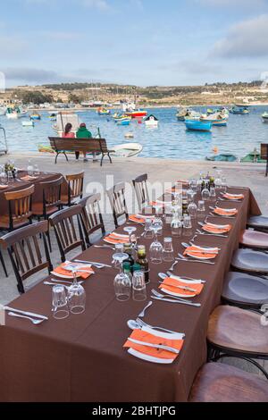 Dining table with places set outdoors on quayside, Marsaxlokk, Malta Stock Photo