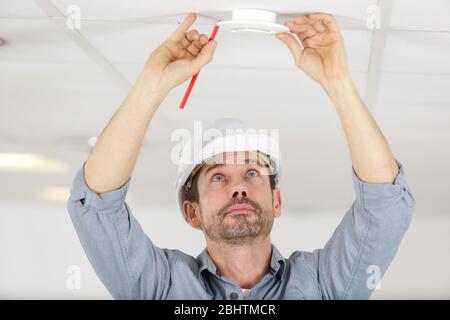 man installing smoke or carbon monoxide detector Stock Photo