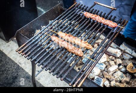 Grilled kebab cooking on wooden skewers. Shashlik during of cooking on the mangal over hot charcoals outdoors, street food Stock Photo