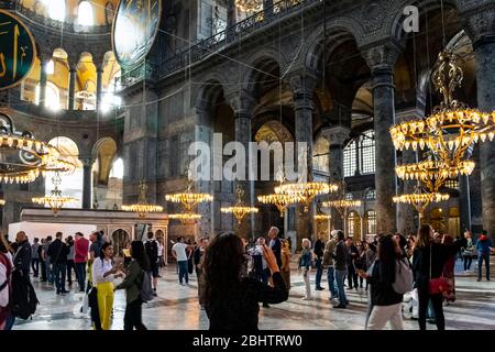 Tourists wander the ornate, somber interior ground level of the Hagia Sophia mosque, now a museum, in Istanbul, Turkey. Stock Photo
