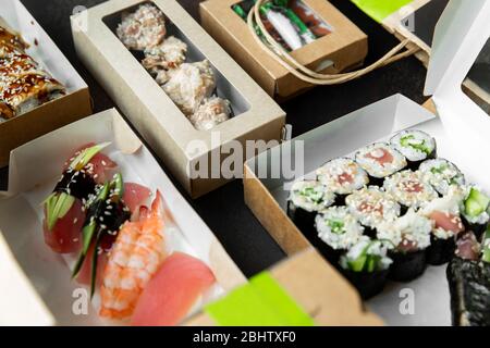 Various selection of sushi, rolls and gunkans in craft boxes on a dark background. Food at home. Delivery concept Stock Photo
