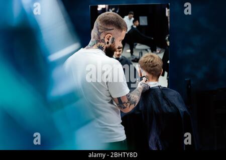Male haircut with electric razor. Tattooed Barber makes haircut for ...
