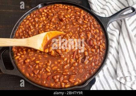 Bourbon Baked Beans in a Cast Iron Skillet: Pork and beans seasoned with bourbon whiskey, molasses, and brown sugar Stock Photo