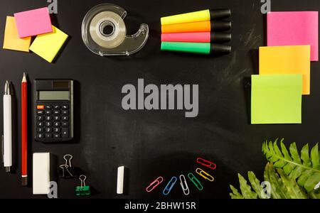 school stationary supplies on black chalkboard background with copy space ready for graphic design, school education learning concept, calculator, pen Stock Photo