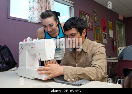 El Paso, Texas USA, May 2010: Male Hispanic student at Mission Early College High School learns to use sewing machine in classroom as fellow student looks on.  ©Bob Daemmrich Stock Photo