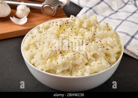 A bowl of homemade garlic mashed potatoes with melting butter and pepper Stock Photo