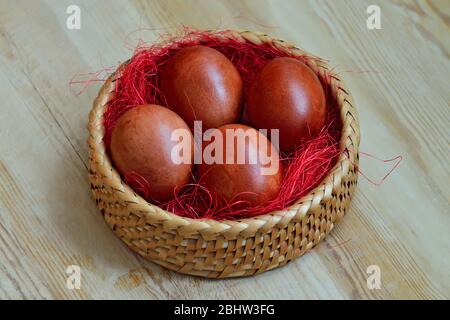 Beautiful dyed chicken eggs lie in a wicker basket Stock Photo