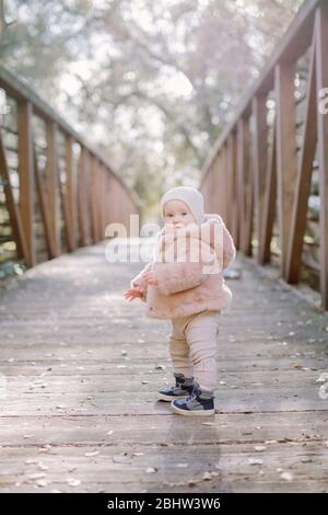 Baby standing on a bridge and looking at camera Stock Photo