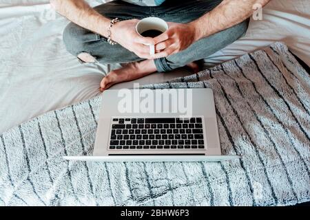 Man drinking coffee while working from bed in Madrid.Spain. Stock Photo