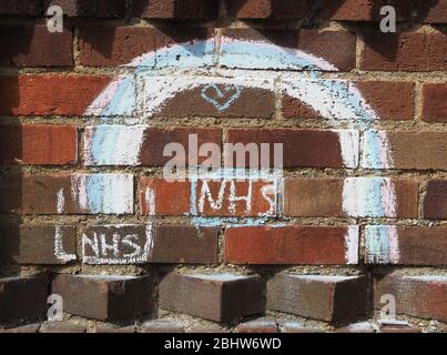 View of a rainbow chalked on a brick wall by children to show support for care workers and the NHS during the coronavirus pandemic of 2020 Stock Photo