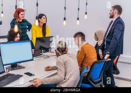 Handsome young executive explaining new employees an online task on theirs computers Stock Photo
