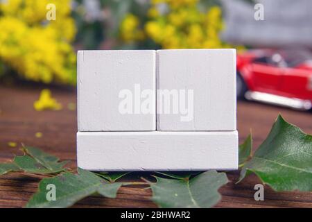 White wood calendar blocks for write the date and branches with yellow flowers over a wooden table. Selective focus with blurred background Stock Photo