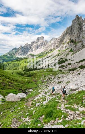 Two hikers on a marked hiking trail from the Adamekhuette to the Hofpuerglhuette, view of mountain ridge with mountain peak Grosse Bischofsmuetze Stock Photo