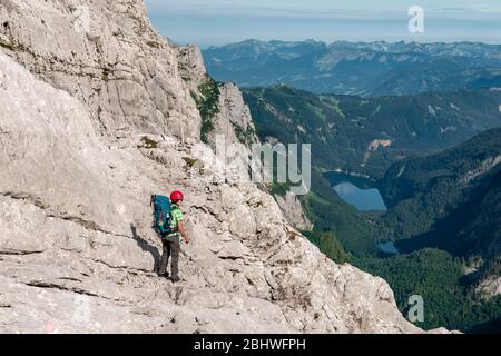 Hiker on rocky route from Simonyhuette to Adamekhuette, rocky alpine terrain, view of mountain panorama and Vorderer Gosausee, Salzkammergut, Upper Stock Photo