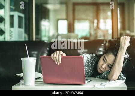 Depressed Asian woman is sitting at a desk in the house. She work from home or WFH because problem of covid19 or coronavirus outbreak Stock Photo