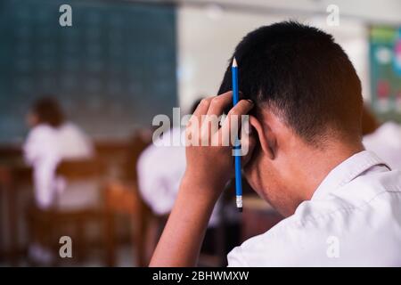 School students thinking and taking exam answer in classroom with stress Stock Photo