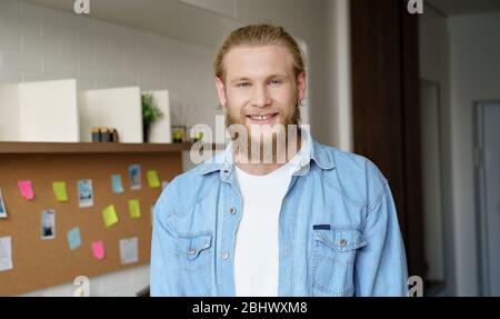 Positive young hipster man standing at home office looking at camera. Head shot Stock Photo